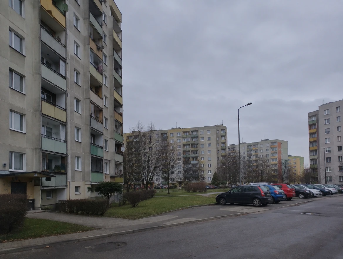 Osiedle z blokami z wielkiej płyty i parkingiem między budynkami